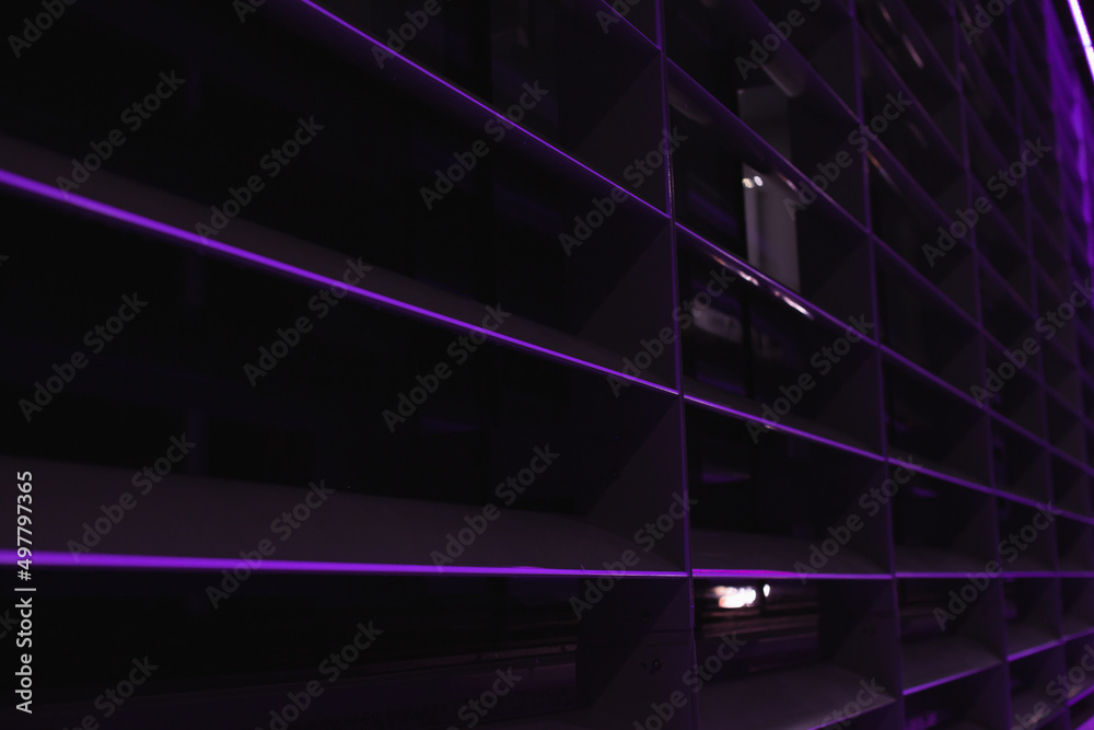 Modern hi-tech style building exterior at night with neon purple violet lights stripes - urban architecture background