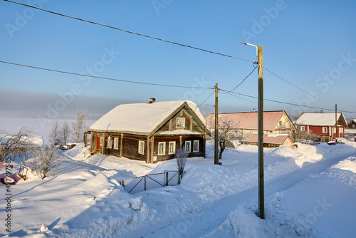 Snowdrifts near buildings in village in winter day.