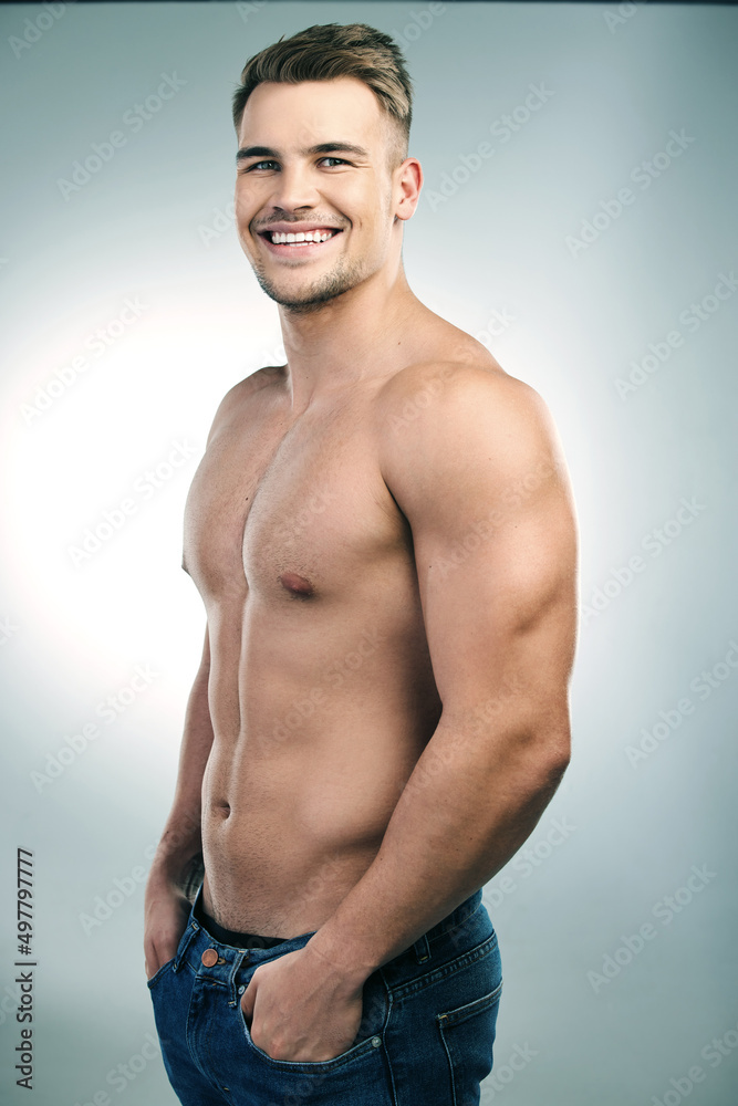 Fototapeta premium Its not magic, these muscles really are all mine. Studio shot of a handsome young man posing shirtless against a grey background.
