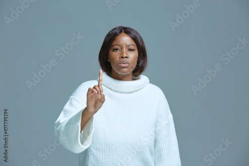 Serious african american woman warning by admonishing gesture, raised finger up, saying no, be careful, giving advice
