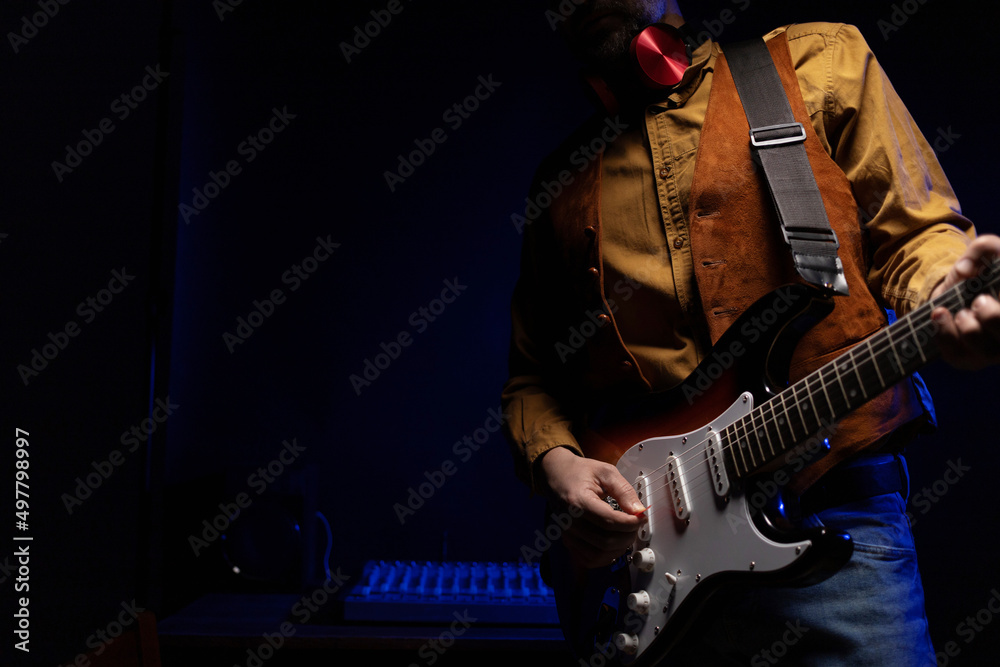 Obraz premium Man playing electric guitar. Musician at record studio holding electric guitar
