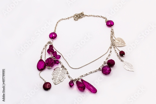 Elegant silver necklace with leaves and magenta stones isolated on white.