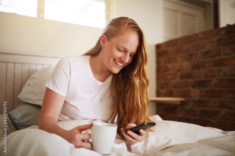First thing in the morning, check texts. Shot of a young woman laying in bed at home.
