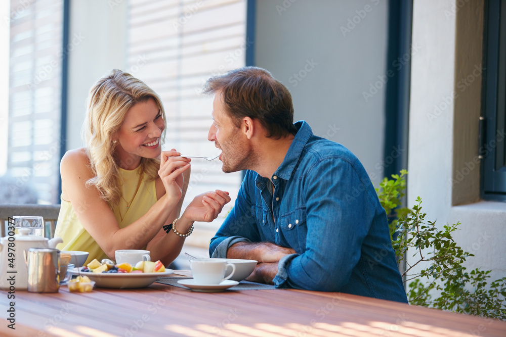 Are you buttering me up. Shot of a happy young woman giving her husband a taste of her food. Are you buttering me up. Shot of a happy young woman giving her husband a taste of her food.