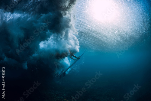 Surfer woman with surfboard dive underwater with under sea wave.