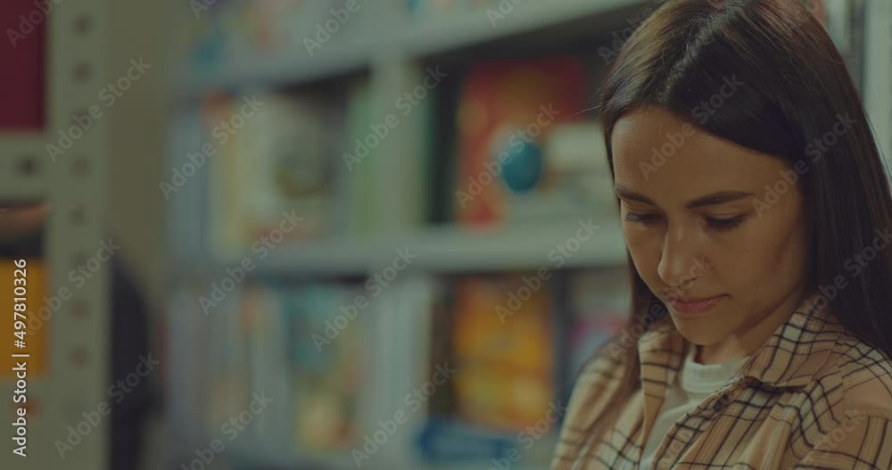 Happy woman looks at a book with interest, readers in the library hall. Beautiful woman looks enthusiastically at the bookshelves, high shelves with shelves of books. 4k, ProRes Happy woman looks at a book with interest, readers in the library hall. Beautiful woman looks enthusiastically at the bookshelves, high shelves with shelves of books. 4k, ProRes