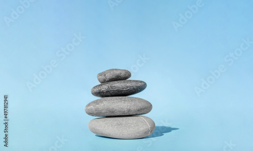Balanced pebble stones for spa treatments on blue background. The balancing cairn - symbol of harmony  tranquility and relaxation  concept of meditation. Stack of spa hot stones.