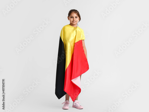 Little girl with flag of Belgium on light background