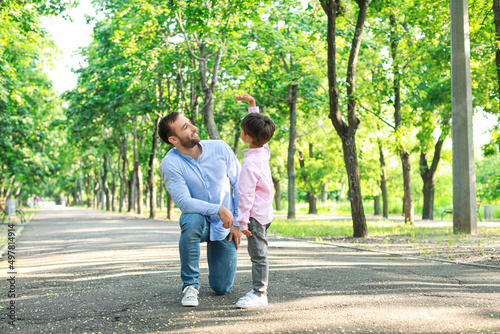 Fototapeta Naklejka Na Ścianę i Meble -  Little boy showing something to his father in park