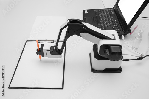 Futuristic robotic arm with pen and blank paper sheet at exhibition photo
