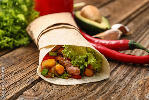 Tasty burrito with meat on wooden background