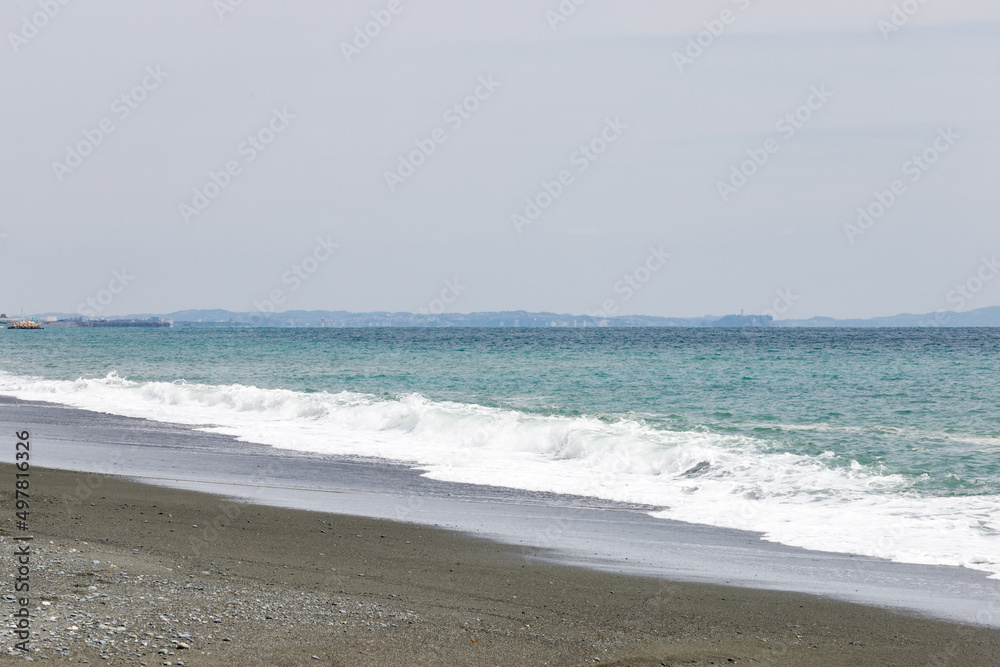 海岸に打ち寄せる波と青い海の向こうに見える房総半島