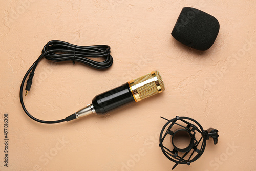 Modern microphone with stand and wire on beige background