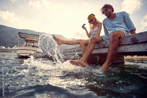 Konstfotografi couple in love flirting and enjoying dangling legs in the lake