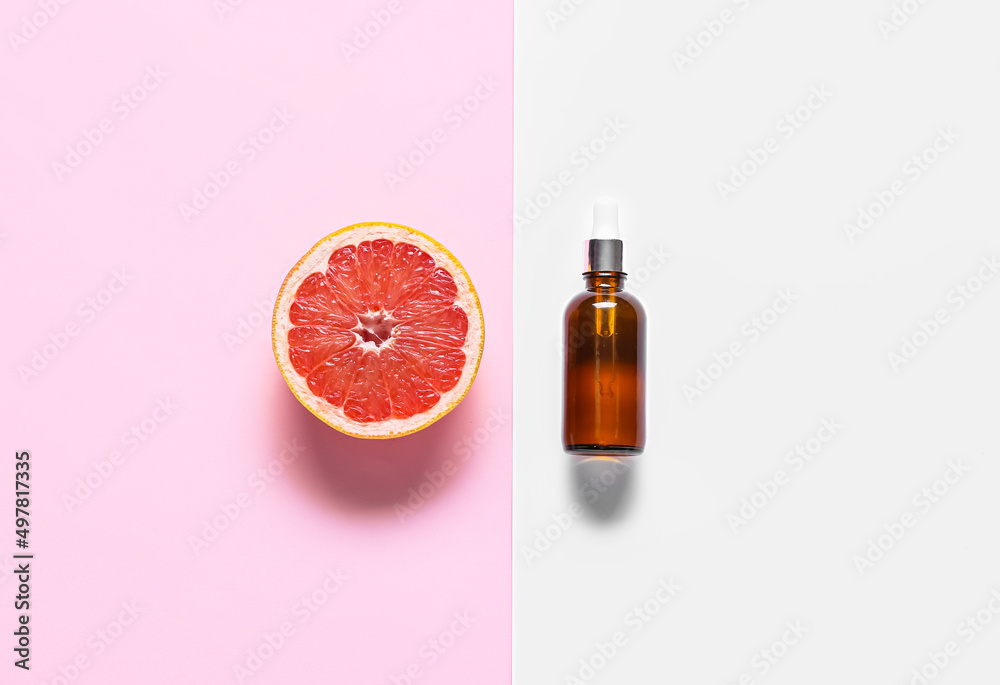 Bottle with essential oil and half of juicy grapefruit on color background Bottle with essential oil and half of juicy grapefruit on color background