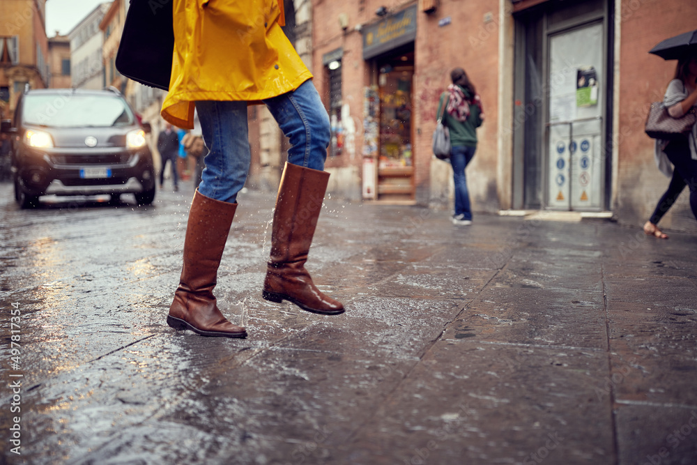 Close-up of legs of a young girl walking on the rain in the city. Walk, rain, city