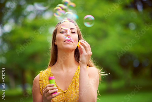 Indulging her inner child. Shot of a carefree young woman blowing bubbles in the park.