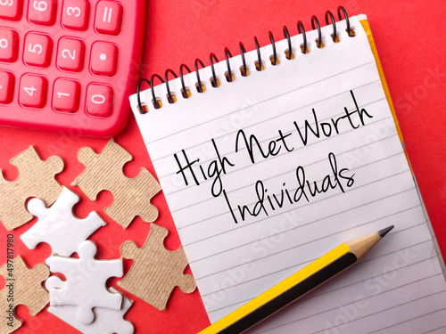 Calculator,puzzle and pencil with text High Net Worth Individuals on red background photo