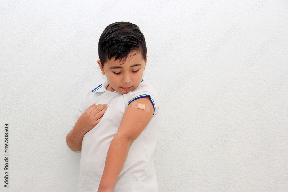 8-year-old Hispanic boy wearing a school uniform shirt happily shows his recently vaccinated arm against Covid-19 in the new normality due to the Coronavirus pandemic
8-year-old Hispanic boy wearing a school uniform shirt happily shows his recently vaccinated arm against Covid-19 in the new normality due to the Coronavirus pandemic