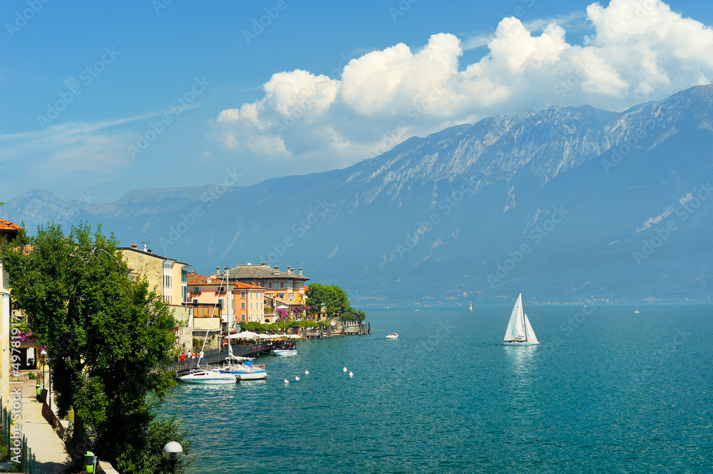 The holiday resort town of Gargnano on Lake Garda, Lombardy, Italy. Sail boat leaving the harbour. Lago di Garda.