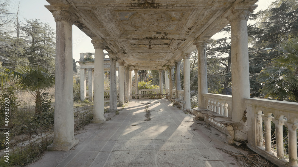 Old abandoned building with white columns. Action. Beautiful perspective with columns of abandoned building. Abandoned corridor with columns in summer forest