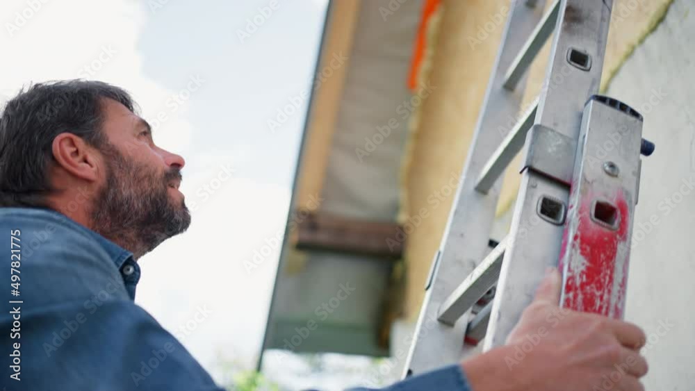 High angle view of mature man climbing up the ladder