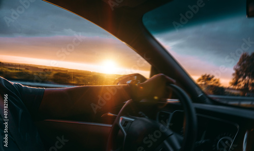 A car is driving on the road under the sunset