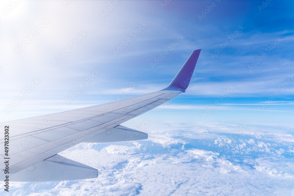 Wing of an airplane cruising above the clouds Wing of an airplane cruising above the clouds