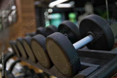 Set of black dumbbell. Metal dumbbells on rack in fitness center. Sport equipment concept.