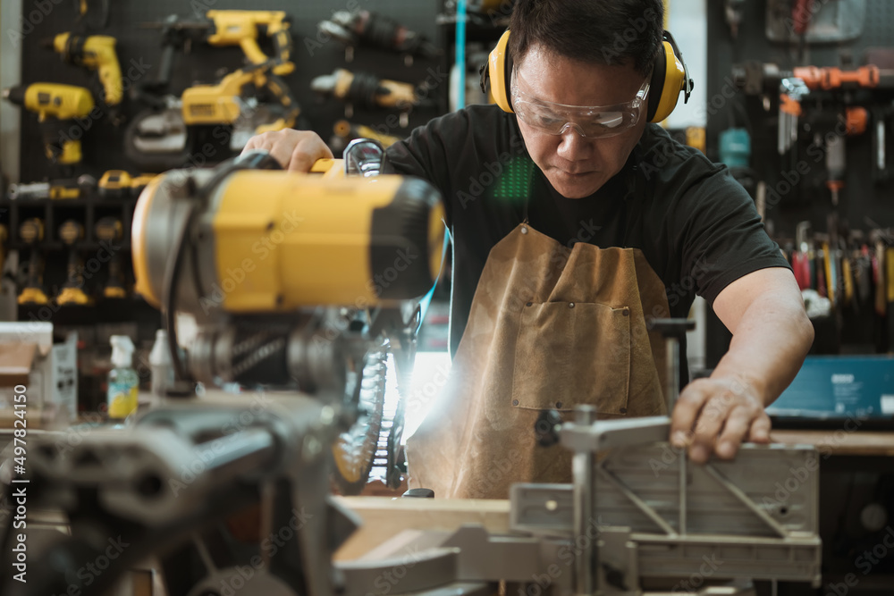 Carpenter cutting wooden with a miter saw or circular saw in shop, woodworking repair and construction tool concept ,selective focus Carpenter cutting wooden with a miter saw or circular saw in shop, woodworking repair and construction tool concept ,selective focus