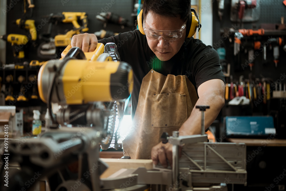 Carpenter cutting wooden with a miter saw or circular saw in shop, woodworking repair and construction tool concept ,selective focus Carpenter cutting wooden with a miter saw or circular saw in shop, woodworking repair and construction tool concept ,selective focus