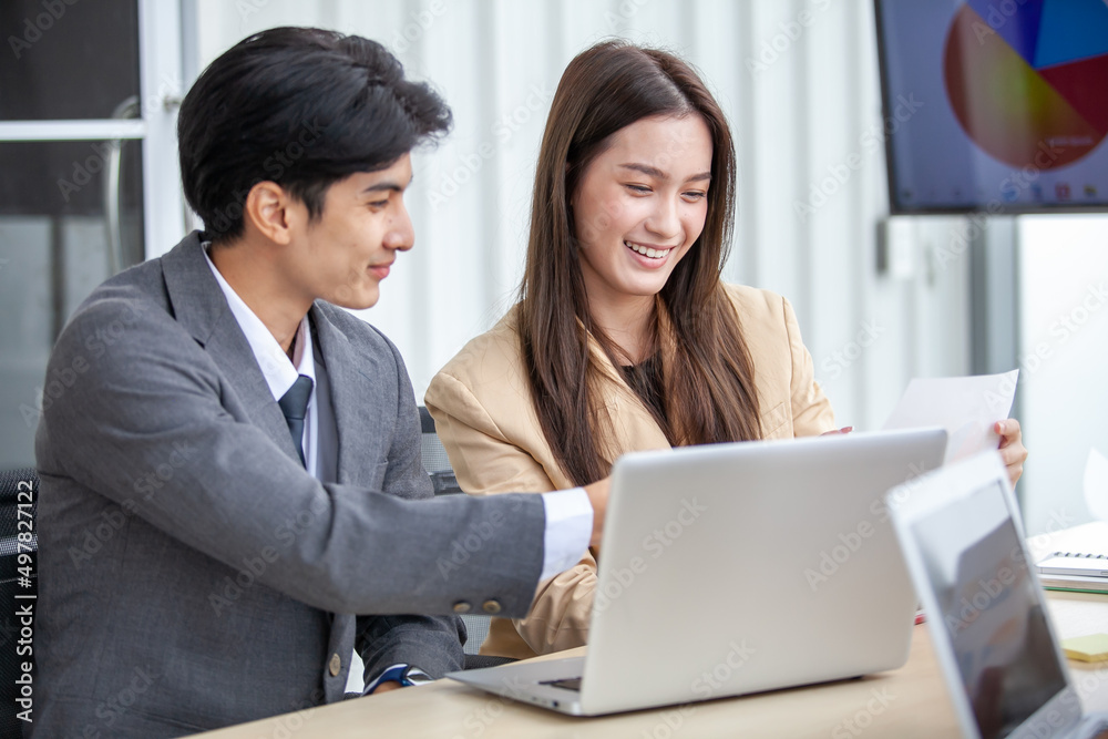 Asian business team male and female colleagues talking at work share ideas with laptop, Happy colleagues work together on computer in office. Asian business team male and female colleagues talking at work share ideas with laptop, Happy colleagues work together on computer in office.