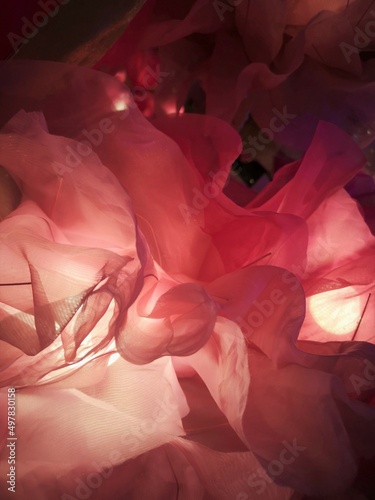 Light passes through the texture of a thin, translucent fabric for a pink-black background.
