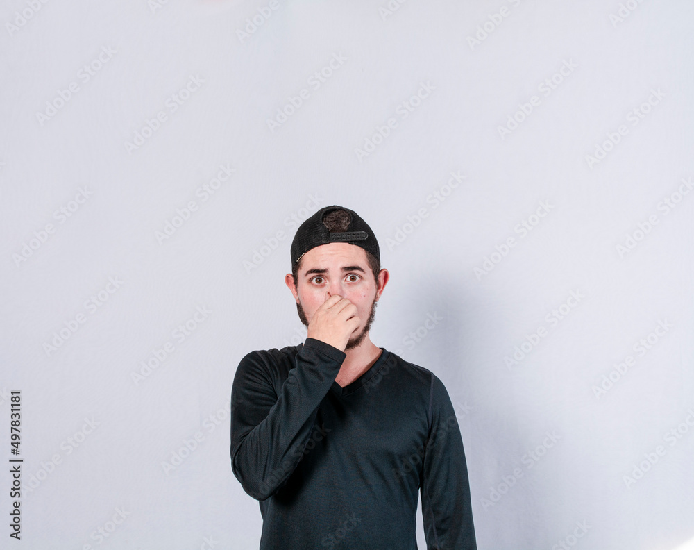 Close up of a man covering his nose, a guy with a face of unpleasant odors, Latino man covering his nose Close up of a man covering his nose, a guy with a face of unpleasant odors, Latino man covering his nose