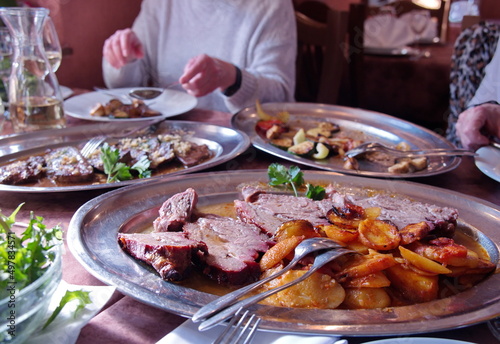 Various food with roasted meet, potatoes and vegetables on rustic table in restaurant