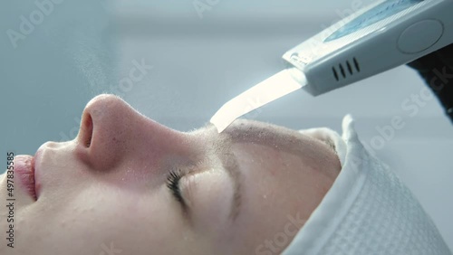 Doctor with ultrasonic scraber. Procedure of ultrasonic cleaning of face. Patient in beauty clinic. Healthcare, clinic, cosmetology.