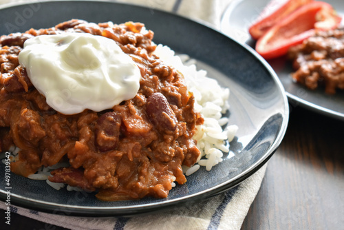 Chilli con carne with minced beef, red kidney beans, onion, paprika, cumin and herbs, with Greek yogurt on the top, and having it with rice.  Traditional Mexican food.