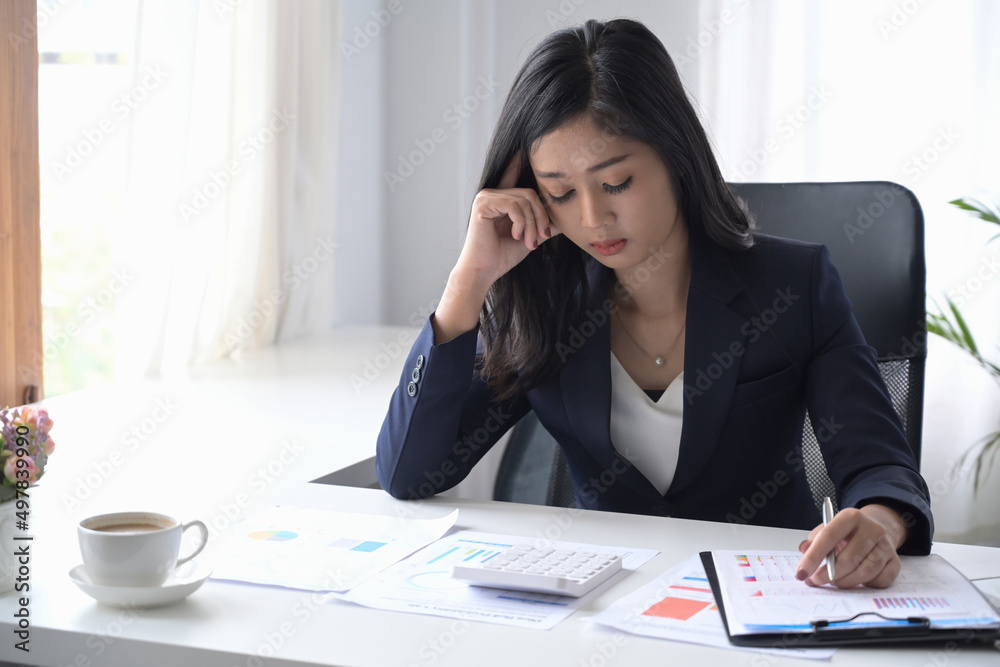 Serious female accountant sitting at her workplace and checking financial document. Serious female accountant sitting at her workplace and checking financial document.