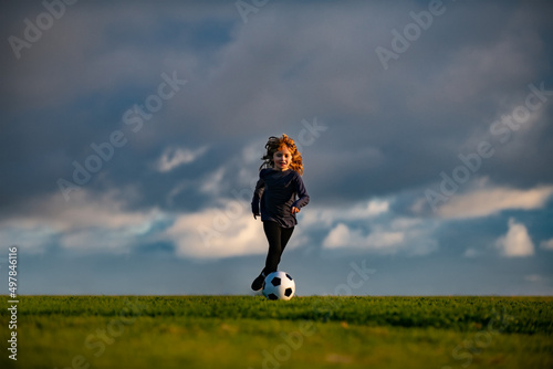 Boy kicking football ball. Soccer boy, child play football. School kids playing football in a field. © Volodymyr