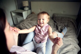 Happy mother with baby toddler on the bed in the bedroom, cozy motherhood and emotions. Bright interior and lifestyle