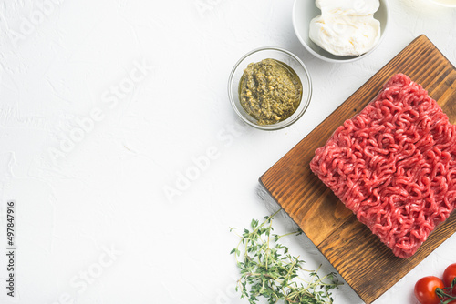 Raw meatballs made from ground beef ingredients, on white stone background, top view flat lay, with copy space for text