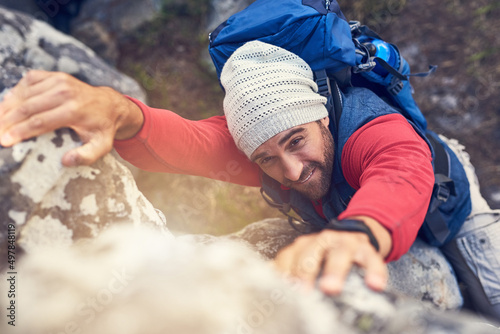 What doesnt kill you makes you stronger. Shot of a happy hiker climbing over rocks on a mountain trail.