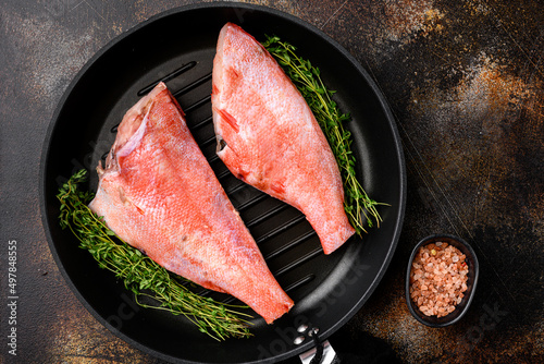 Fresh sea ocean red perch fish, in frying cast iron pan, on old dark rustic table background, top view flat lay