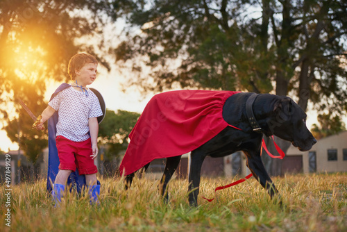 Theyre making headlines. Shot of a little boy and his dog wearing capes while playing outside.