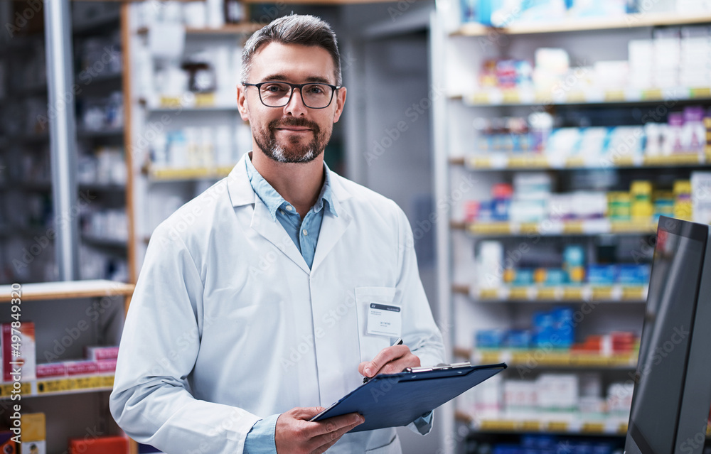 Fototapeta premium If we dont stock what you need, well source it. Portrait of a mature pharmacist writing on a clipboard in a pharmacy.