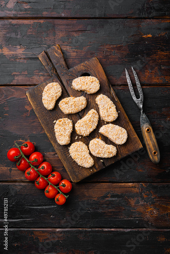 Instant food raw chicken nuggets ready for cooking set, on old dark wooden table background, top view flat lay, with copy space for text
