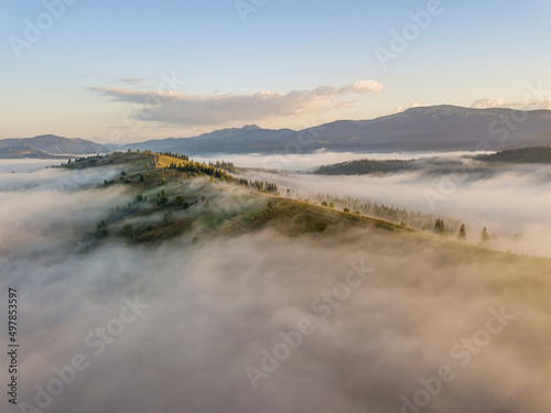 Mountain settlement in the Ukrainian Carpathians in the morning mist. Aerial drone view.