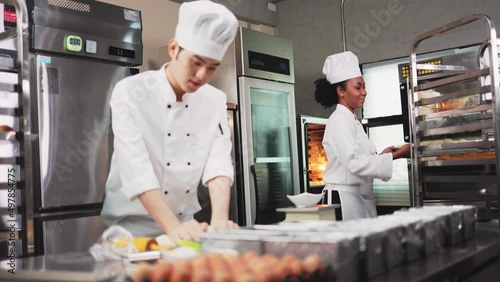 Asian young man chefs  baker in a chef dress and hat, cooking together in kitchen.Team of professional cooks in uniform preparing meals for a restaurant.