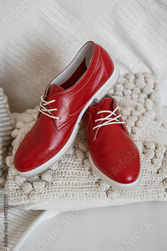 Red shoes with white laces, which are on a white knitted scarf, close-up