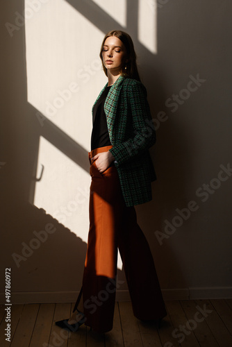 A model girl standing in the rays of the sun. the girl in the reflection of light from the window